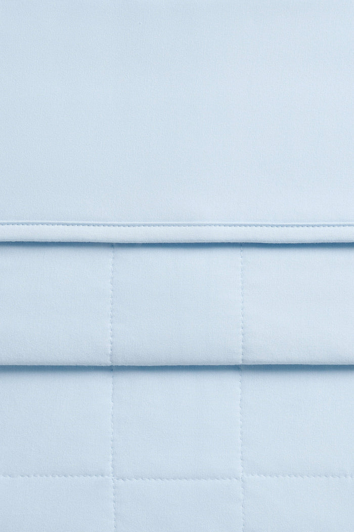 Close up of quilted backing and smooth top side of the Adult Quilted Blanket in Breeze 1.0