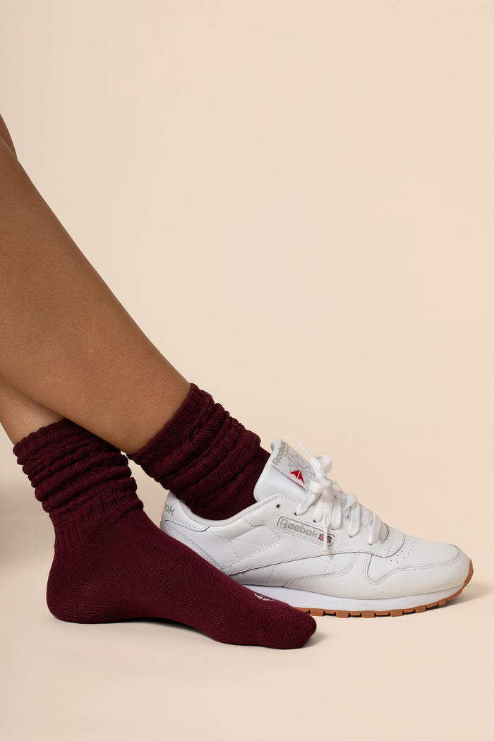 White sneakers with maroon socks on a beige background