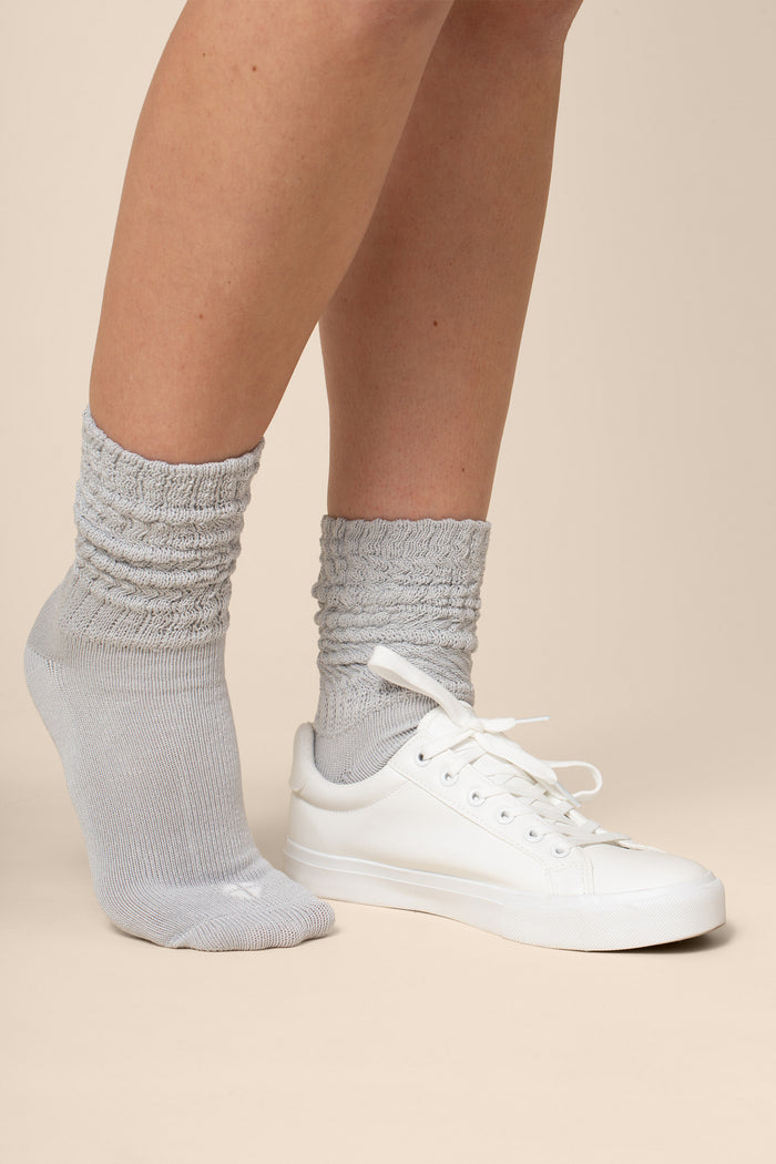 Gray socks worn with white sneakers on a beige background