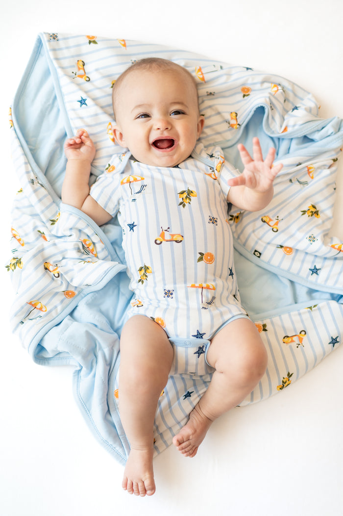 Smiling infant laying on a Baby Blanket in Amalfi Coast 1.0 wearing the matching short sleeve bodysuit