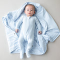 Baby in a blue footie laying on a baby blanket