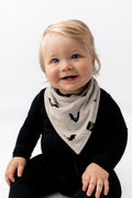 Baby smiling in Bib in Bats print over black romper sitting on a white background
