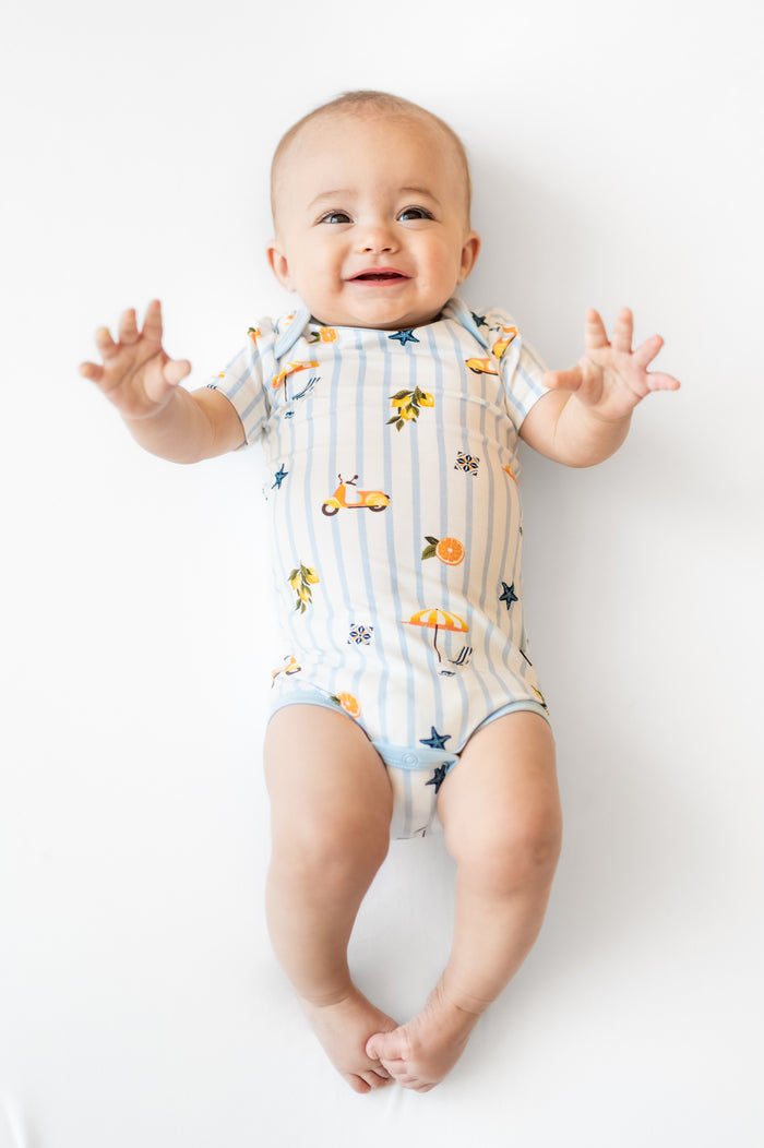Infant wearing the Bodysuit in Amalfi Coast laying on a white surface