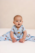 Baby wrapped in Curious George 1.0 print Baby Blanket wearing similar print bodysuit on a beige background