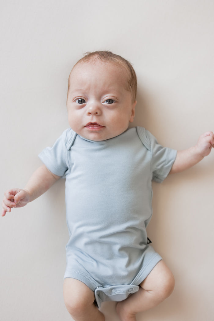 Close up of Baby wearing Bodysuit in Fog color on a beige background