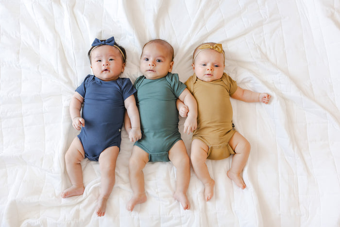 Three babies laying down with short sleeve bodysuits on