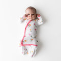 Newborn laying down on a white surface wearing the Bundler in Tulip