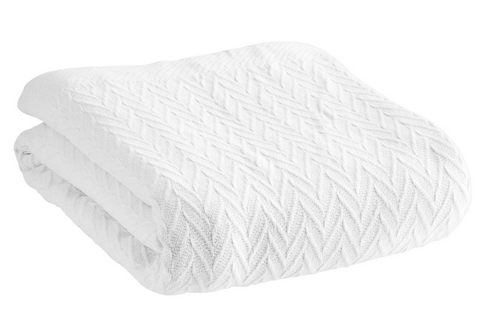 Displayed against a white background is the Cotton Thermal Blanket by 1888 Mills, featuring a folded, white knitted design crafted from premium 100% cotton. Its chevron pattern with raised zigzag lines enhances its cozy and warm appearance. The blanket boasts neatly finished edges and exudes a soft, hotel-quality allure that is inviting.
