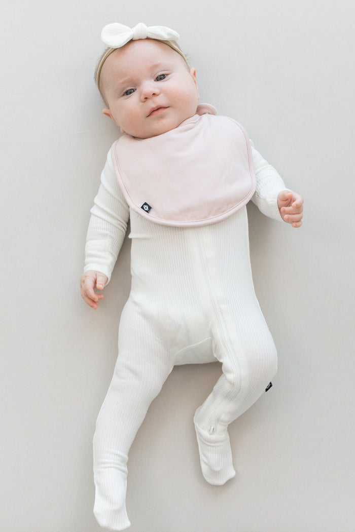 Infant wearing Kyte Baby Cushy Bib in Blush