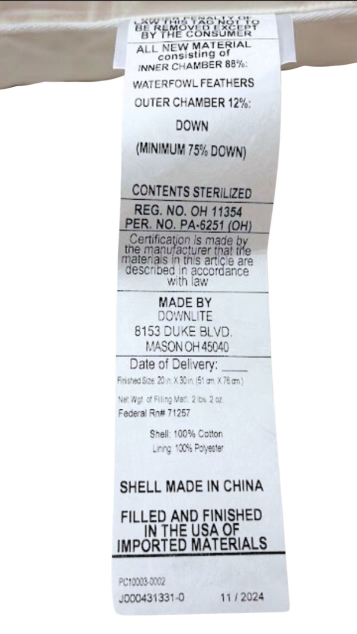 A white label with black text lists materials—outer chamber: 12% down, inner: 88% waterfowl feathers. It notes the three-chamber design of the Pillow Factory Downlite Down Halo, sterilization, care instructions, and manufacturer details.