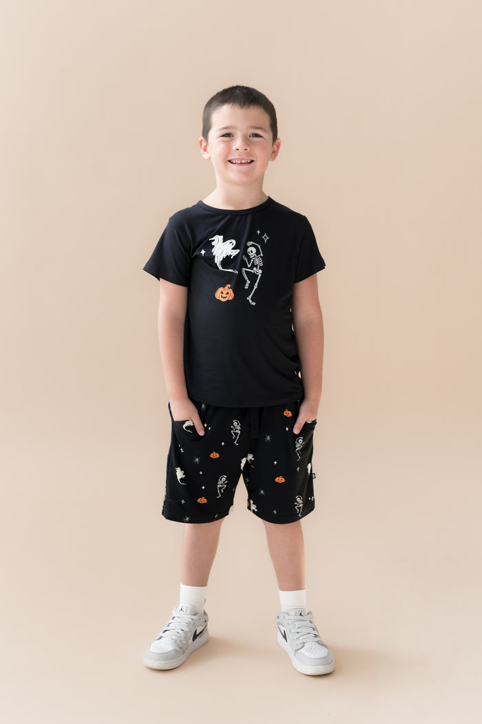 Boy wearing Drawstring Short in Halloween Friends print under Black T-shirt on a beige background