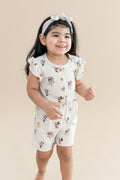Child wearing mickey mouse and friends printed flutter sleeve romper with buttons on the front and cream bow