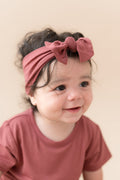 Child wearing Toddler Basic Tee in Ember with similar color knotted bow headband