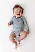 Baby wearing a light blue onesie on a white background