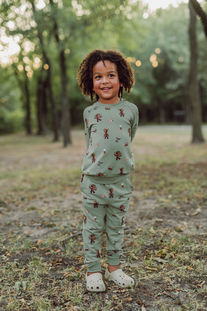 boy outside with his hands behind his back wearing groot jogger set and smiling.