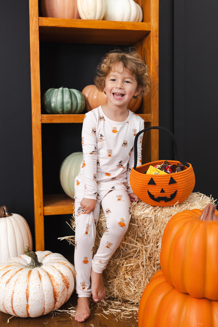 Boy sitting with Halloween pumpkin decorations wearing Long Sleeve Pajamas in Halloween Teddy print
