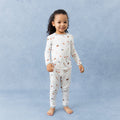 Young girl standing in front of a marbled background wearing the Long Sleeve Pajamas in Home Run