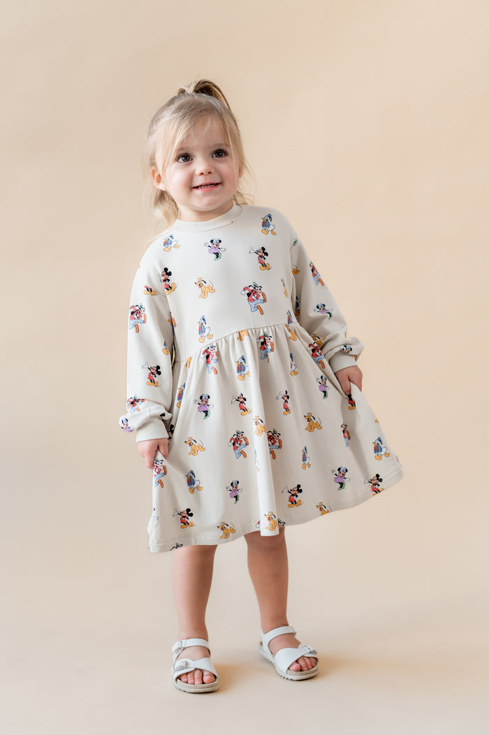 Toddler girl smiling wearing a long sleeve skater dress in mickey mouse & friends.