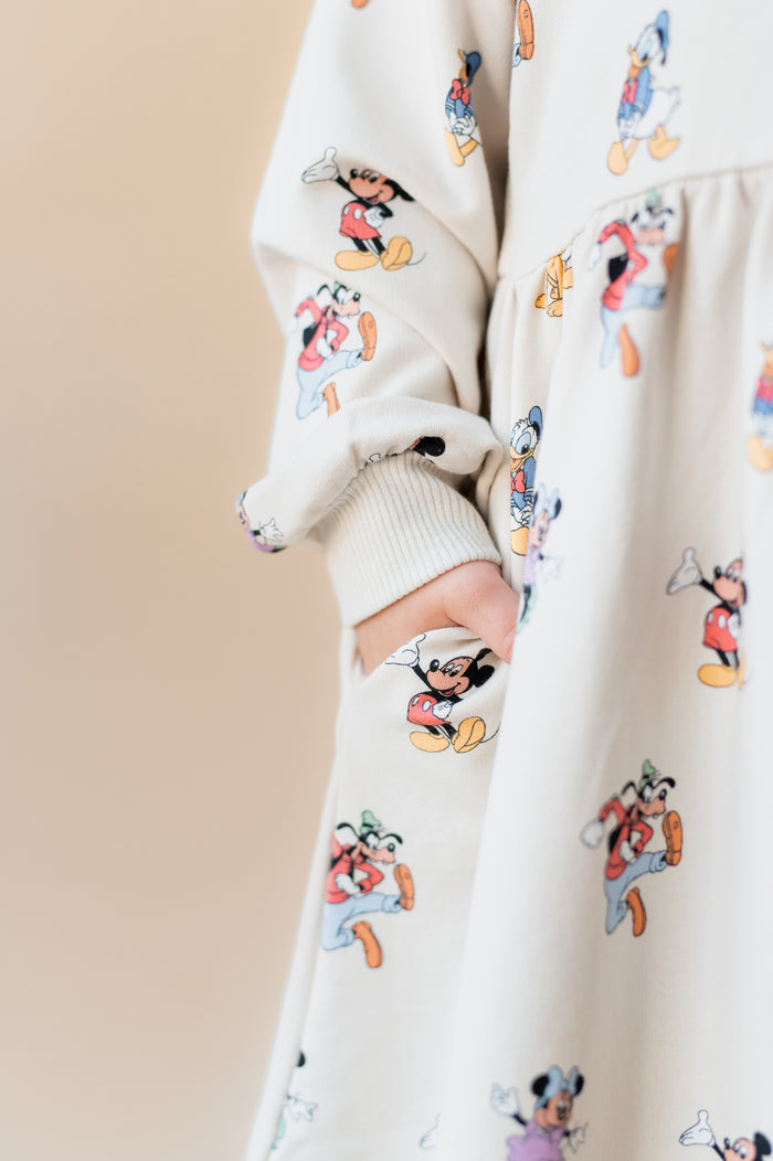Girls hand in her pocket wearing mickey mouse & friends dress.