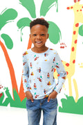 Boy standing in front of a colorful background wearing Long Sleeve Toddler Crew Neck Tee in Curious George print over a blue jeans