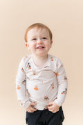 Boy wearing Long Sleeve Toddler Crew Neck Tee in Halloween Teddy print over black shorts on a beige background