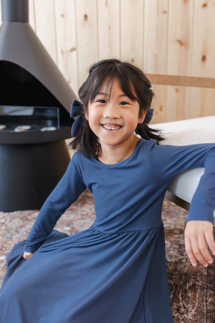 Girl wearing Long Sleeve Twirl Dress in Oxford sitting near chimney