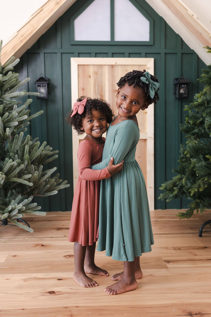 two girls hugging wearing ember and pine long sleeve bodysuit dresses.