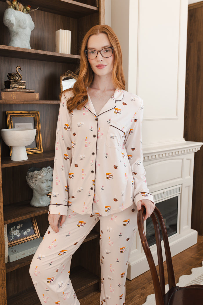 Modal wearing Long-Sleeved Women's Pajama Set in Book Club print posing in a living room
