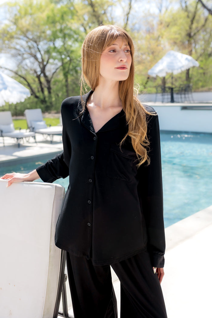 Female model standing by the pool wearing the Long-Sleeved Women's Pajama Set in Midnight with Midnight Trim