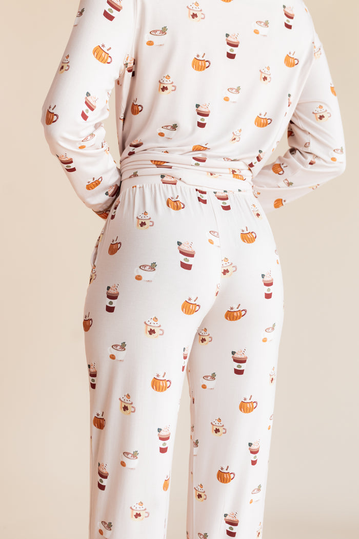 Back side of Model wearing Long-Sleeved Women's Pajama Set with Pumpkin Spice Latte print on a beige background