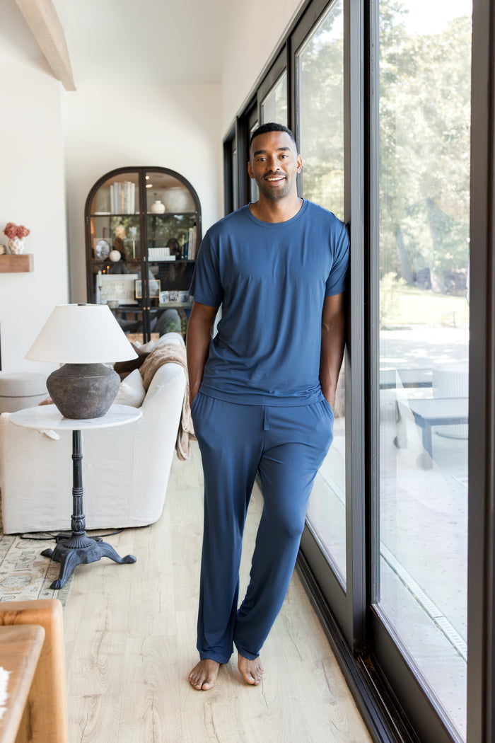 Model wearing Men's Crew Neck Tee in Oxford over Men's Lounge Pants in Oxford standing against a window in a living room