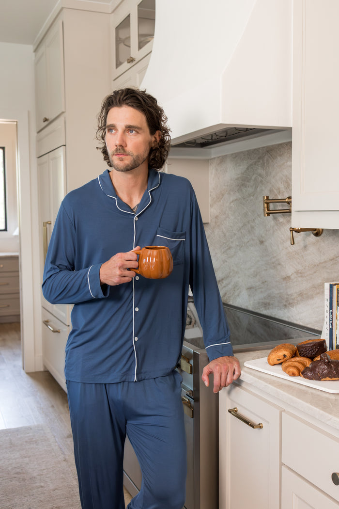 Model wearing Men's Long Sleeve Pajama Set in Oxford standing in a kitchen with a mug