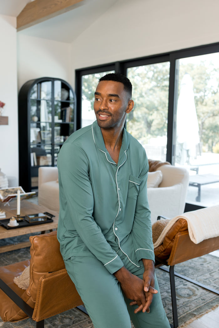 Model sitting in a living room wearing Men's Long Sleeve Pajama Set in Pine
