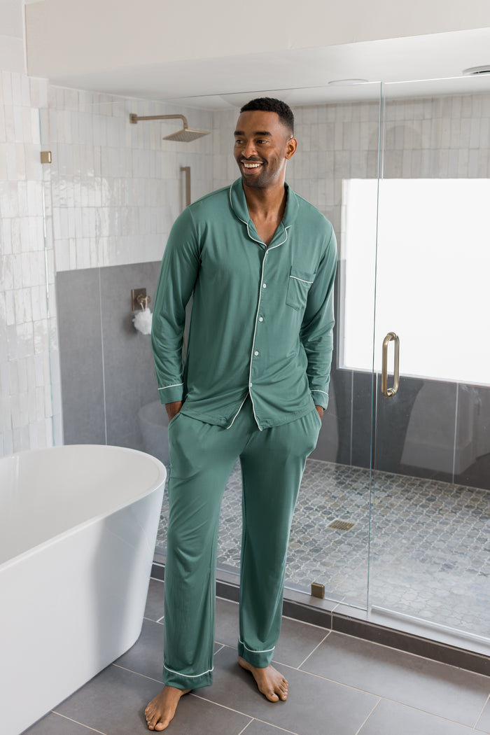 Model wearing Men's Long Sleeve Pajama Set in Pine standing in a bathroom