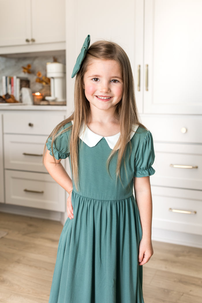 Girl wearing Peter Pan Collar Dress in Pine while standing in kitchen