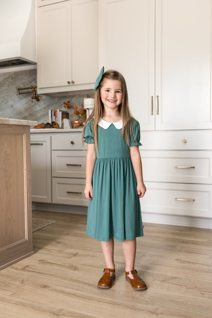 Girl wearing Peter Pan Collar Dress in Pine while standing in kitchen