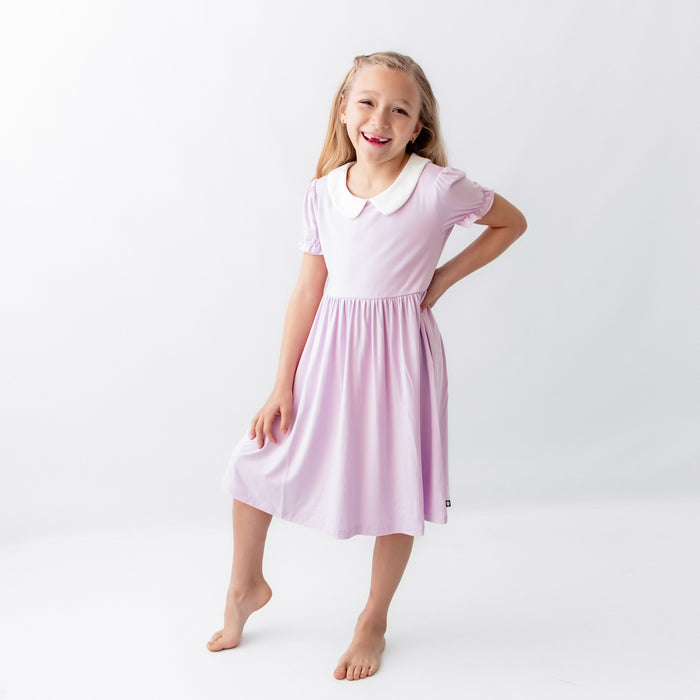 Smiling girl modeling the Peter Pan Collar Dress in Thistle in front of a white background