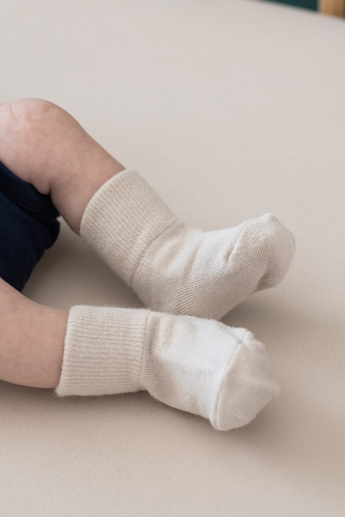 Newborn wearing Kyte Baby Quarter Socks in Neutral Tan