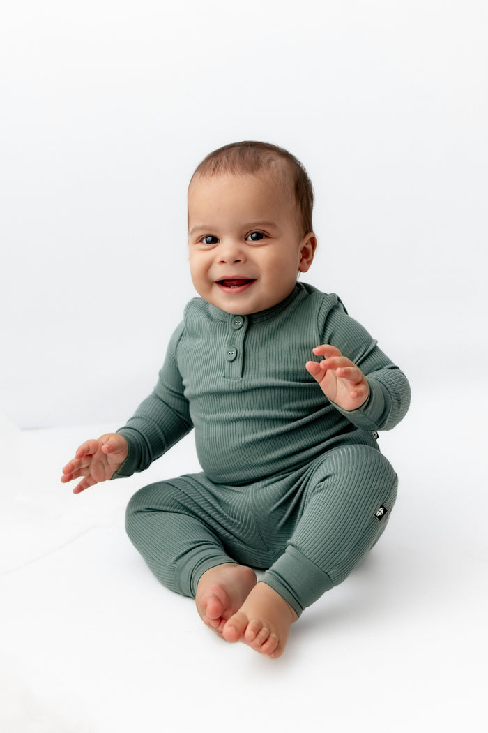 Baby sitting in Ribbed Infant Henley Set in Pine on a white background