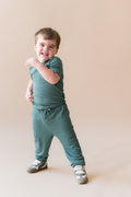 Child wearing Ribbed Jogger Pant in Pine on a beige background