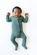 Baby sleeping in Ribbed Zipper Footie in Pine on a white background