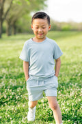 Young boy walking wearing the Short Sleeve Jogger Set in Fog with his hands in the shorts pocket