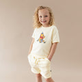 Young girl modeling the Short Sleeve Jogger Set in Winnie the Pooh on Chamomile with the hands in the pockets of the shorts