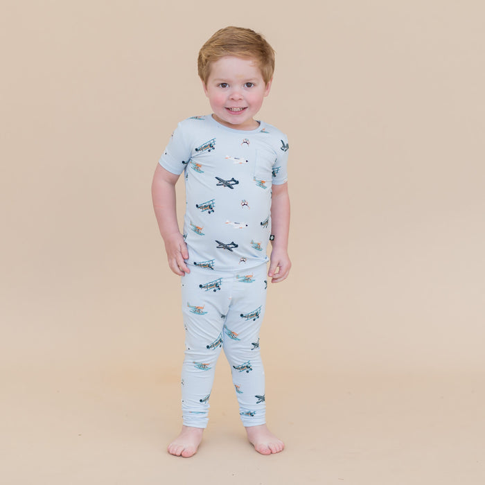 Young boy standing in front of a light taupe background wearing the Short Sleeve with Pants Pajamas in Take Off