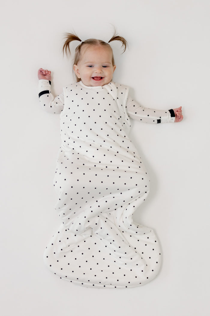 Baby smiling in Sleep bag with Midnight Polka Dot print on a white background