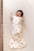 Baby smiling in Sleep Bag with Pumpkin Spice Latte 1.0 print on a beige crib sheet