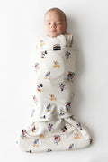Baby asleep in kyte baby sleep bag swaddler with mickey and friends pattern