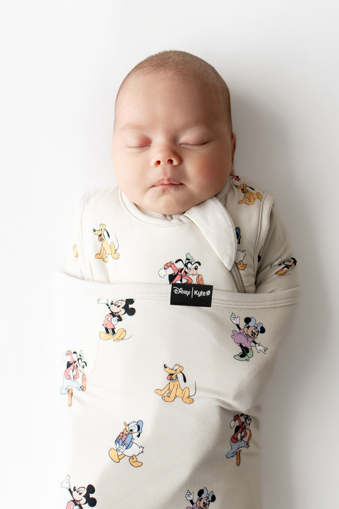 Baby sleeping in a Disney-themed baby swaddle on a white background