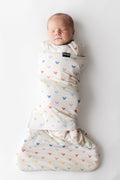 Newborn baby swaddled in a colorful mickey-patterned swaddle on a white background