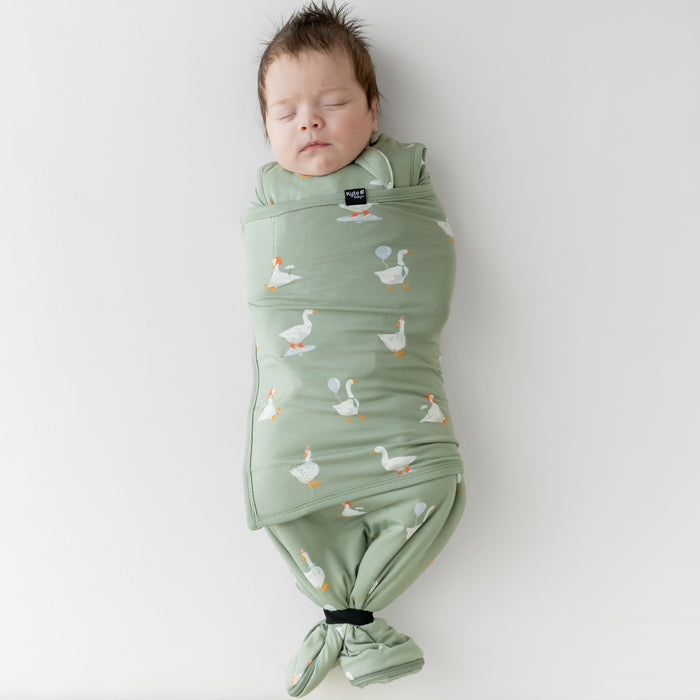 Sleeping newborn swaddled in the Sleep Bag Swaddler in Silly Goose 1.0 with the elastic band wrapping the bottom of the sleep bag